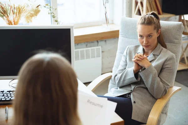 Giovane donna in giacca e cravatta seduta in ufficio durante il colloquio di lavoro con dipendente donna, capo o HR-manager, parlando, pensando, sembra fiducioso — Foto Stock