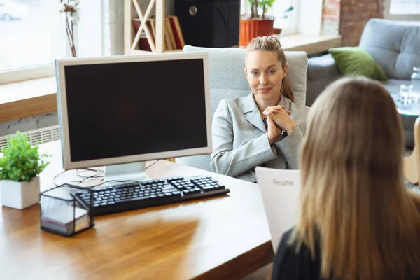 Giovane donna in giacca e cravatta seduta in ufficio durante il colloquio di lavoro con dipendente donna, capo o HR-manager, parlando, pensando, sembra fiducioso — Foto Stock