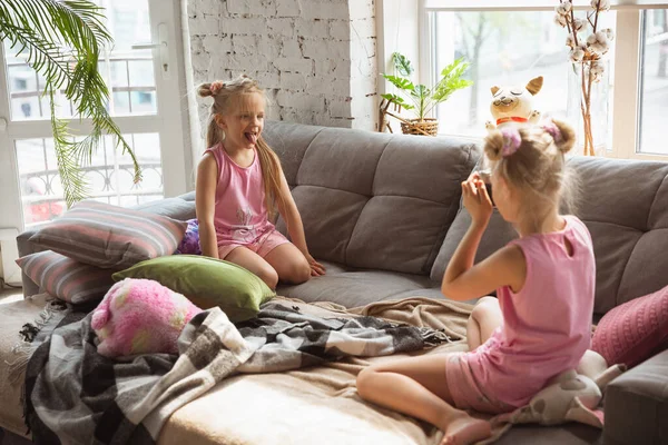 Tiché holčičky hrají v ložnici v roztomilé pyžamo, domácí styl a pohodlí, fotografování, baví — Stock fotografie