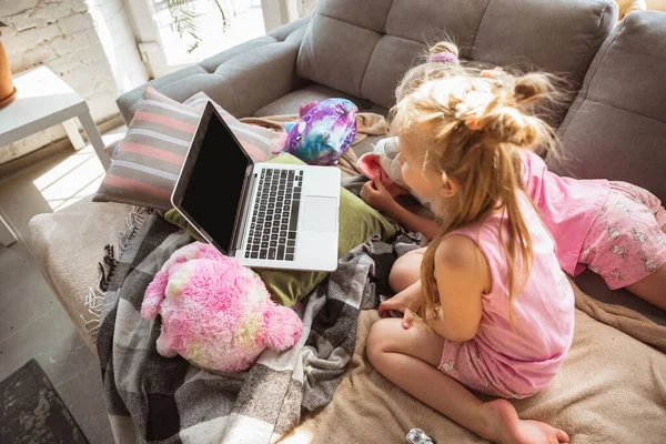 Quiet little girls playing in a bedroom in cute pajamas, home style and comfort, watching cartoons, cinema, having fun
