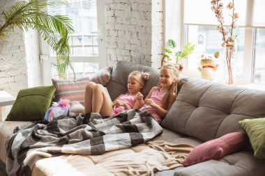 Sessiz küçük kızlar yatak odasında pijamalarıyla oynuyorlar, ev tarzı ve konforu, çizgi film ve sinema izleyip eğleniyorlar.