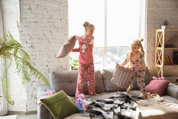 Tiché holčičky hrají v ložnici v roztomilé pyžamo, domácí styl a pohodlí, smích a bojové polštáře — Stock fotografie