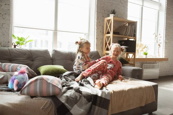 Petites filles tranquilles jouant dans une chambre en pyjama mignon, style maison et confort, riant et combattant oreillers — Photo