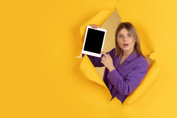 Joyeux jeune femme pose dans fond de trou de papier jaune déchiré, émotionnel et expressif — Photo