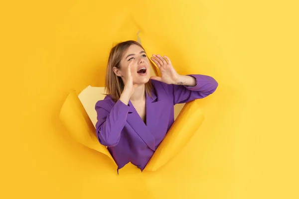 Jovem alegre posa em rasgado papel amarelo buraco fundo, emocional e expressivo — Fotografia de Stock