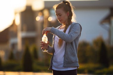 Genç bayan koşucu, gün ışığında şehir caddesinde koştuktan sonra dinlenen sporcu. Güzel beyaz kadın eğitimi, müzik dinlemek.