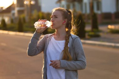 Genç bayan koşucu, gün ışığında şehir caddesinde koştuktan sonra dinlenen sporcu. Güzel beyaz kadın eğitimi, müzik dinlemek.