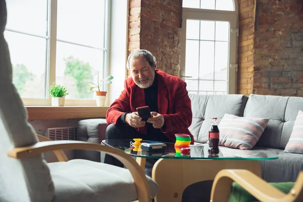 Portrait of senior man with retro toys, meeting things from the past and having fun, exploring the lifestyle of the nineties, playing with rainbow spring toy and tetris — Stock Photo, Image