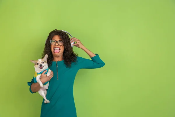 Afro-americanos hermosas mujeres jóvenes retrato con perrito en fondo de estudio verde, emocional y expresivo. Copyspace para anuncio . — Foto de Stock