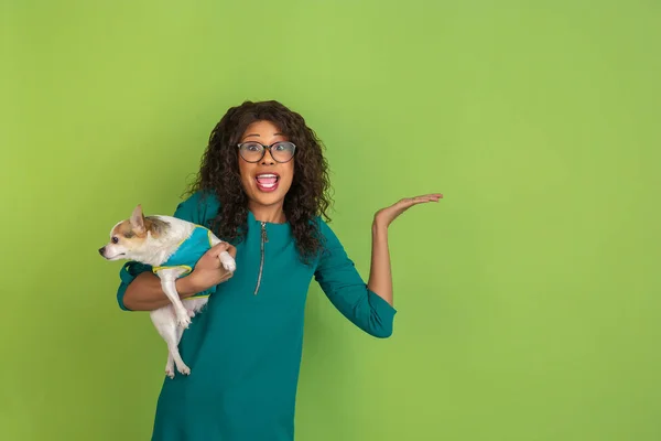 Afro-americanos hermosas mujeres jóvenes retrato con perrito en fondo de estudio verde, emocional y expresivo. Copyspace para anuncio . — Foto de Stock