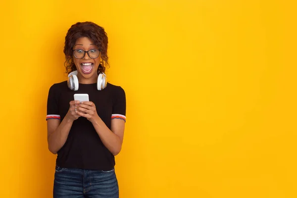 Африканско-американский красивый портрет молодых женщин с беспроводными наушниками на желтом фоне студии, эмоциональный и выразительный. Копирование для рекламы . — стоковое фото