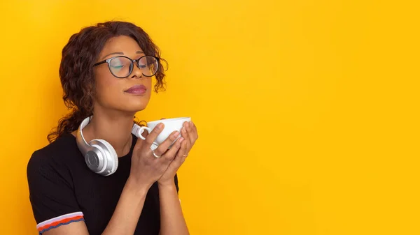 Afro-americanos hermosas mujeres jóvenes retrato con auriculares inalámbricos en fondo de estudio amarillo, emocional y expresivo. Copyspace para anuncio . — Foto de Stock