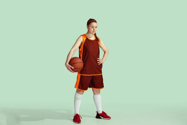 Kafkasyalı genç bayan basketbolcuya karşı naneli renkli stüdyo arka planı — Stok fotoğraf