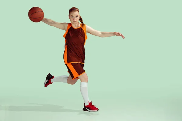 Jonge Kaukasische vrouwelijke basketbalspeler tegen mint gekleurde studio achtergrond — Stockfoto