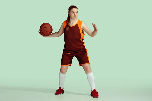 Young caucasian female basketball player against mint colored studio background — Stock Photo, Image