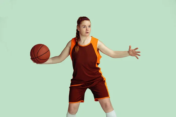 Young caucasian female basketball player against mint colored studio background — Stock Photo, Image