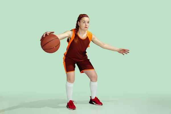 Jonge Kaukasische vrouwelijke basketbalspeler tegen mint gekleurde studio achtergrond — Stockfoto