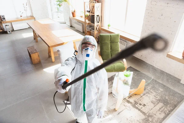 Coronavirus-Pandemie. Ein Desinfektor in Schutzanzug und Maske sprüht Desinfektionsmittel in Haus oder Büro — Stockfoto