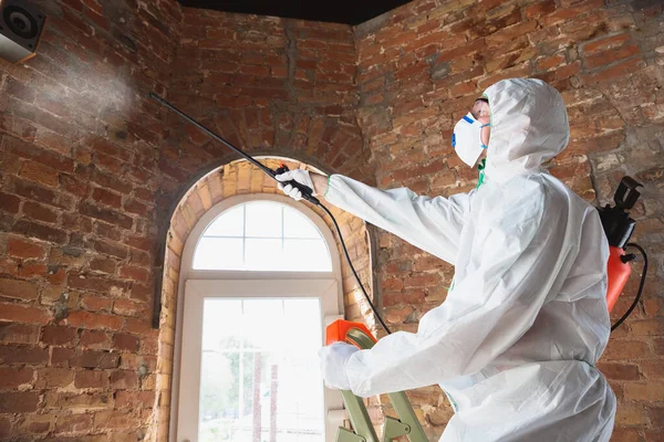 コロナウイルス流行。保護服及びマスク中の消毒剤は、家又は事務所に消毒剤を噴霧します — ストック写真