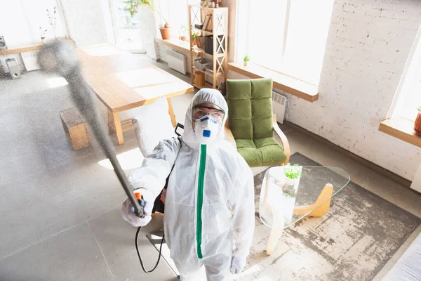 Coronavirus-Pandemie. Ein Desinfektor in Schutzanzug und Maske sprüht Desinfektionsmittel in Haus oder Büro — Stockfoto