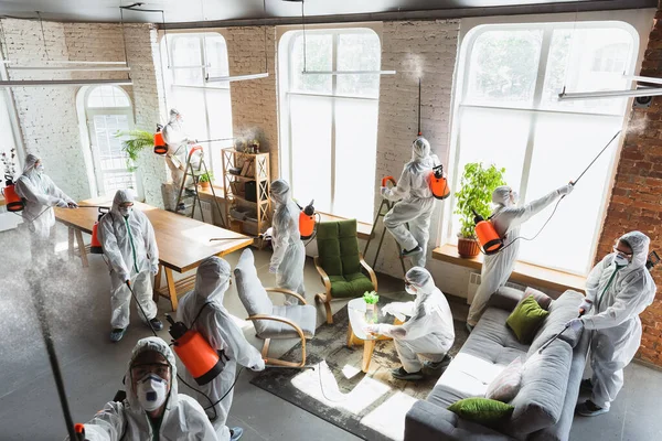 Pandemia por Coronavirus. Un desinfectante con traje protector y mascarilla pulveriza desinfectantes en la casa u oficina —  Fotos de Stock