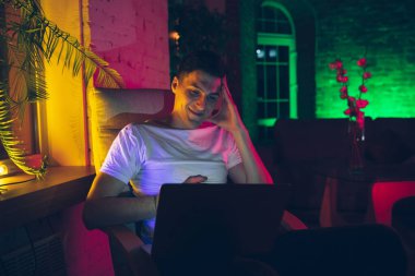 Yakışıklı bir gencin sinematik portresi. Cihazlar, neon ışıklı iç mekânlar. Gençlik kültürü, parlak renkler