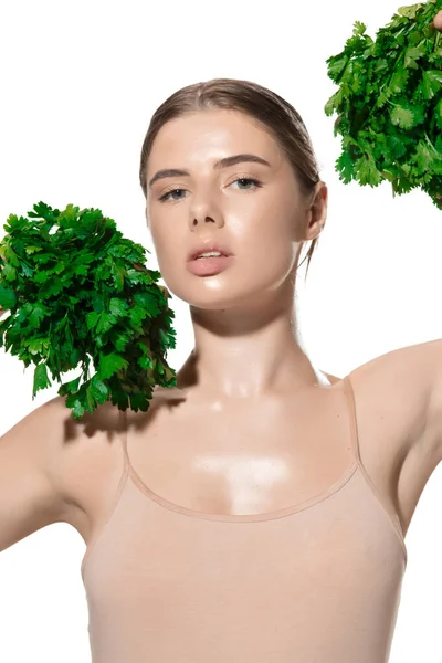 Vitaminen. Close-up van mooie jonge vrouw met groene bladeren op haar gezicht over witte achtergrond. Cosmetica en make-up, natuurlijke en eco-behandeling, huidverzorging — Stockfoto