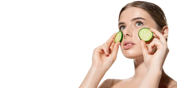 De la naturaleza. Hermosa joven con pepino fresco en su cara sobre fondo blanco. Cosméticos y maquillaje, tratamiento natural y ecológico, cuidado de la piel. Volante . — Foto de Stock