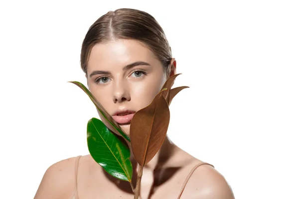 Korunma. Beyaz arka planda yeşil yaprakları olan güzel genç bir kadın. Kozmetik ve makyaj, doğal ve eko tedavi, cilt bakımı — Stok fotoğraf