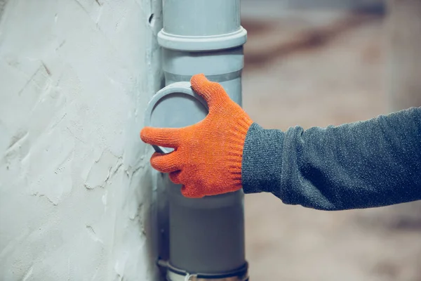 Detailní záběr rukou opraváře, profesionálního stavitele pracujícího v interiéru, instaluje kanalizaci, potrubí — Stock fotografie