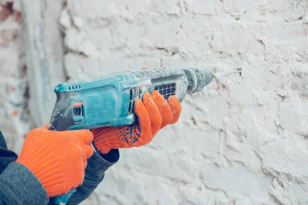 El primer plano de las manos del reparador, el constructor profesional que trabaja en el interior, taladra la pared —  Fotos de Stock