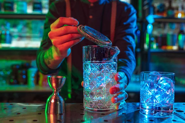 Close up de barman termina preparação de coquetel alcoólico em luz de néon multicolorida — Fotografia de Stock