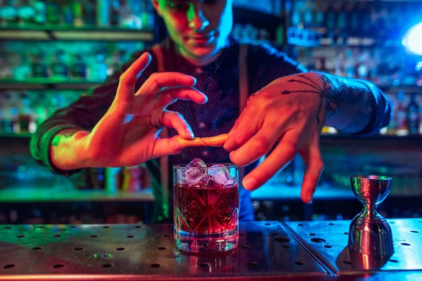 Nahaufnahme vom Barmann beendet die Zubereitung eines alkoholischen Cocktails in buntem Neonlicht — Stockfoto