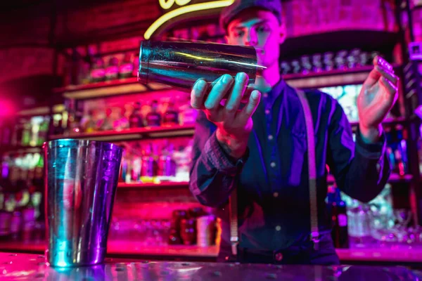 A csapos befejezi az alkoholos koktél elkészítését rázógéppel többszínű neonfényben — Stock Fotó