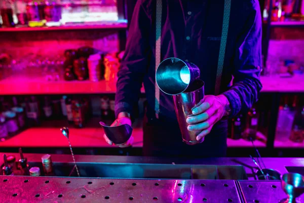 Close up de barman termina preparação de coquetel alcoólico com agitador em luz de néon multicolorida — Fotografia de Stock