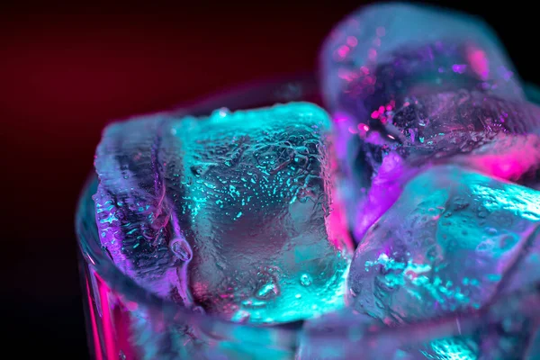 Nahaufnahme von Eiswürfeln im Glas mit alkoholischen Cocktails, Getränken, Getränken in buntem Neonlicht — Stockfoto