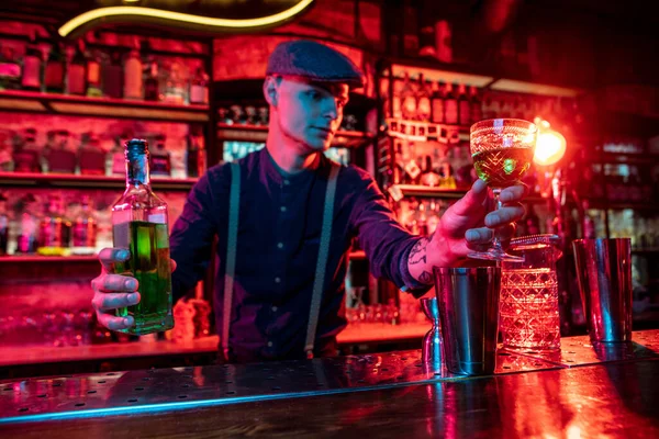 Barman proposing alcoholic cocktails, shots, beverages to guest in multicolored neon light