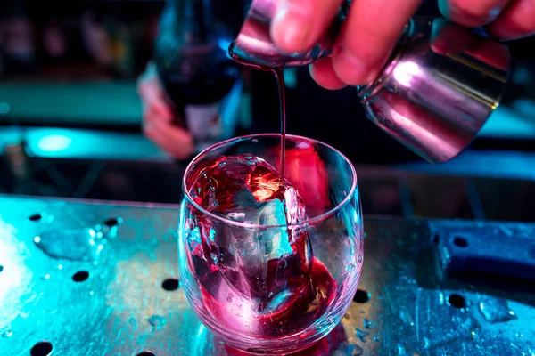 Primer plano de barman preparando cóctel alcohólico con disparo en luz de neón multicolor — Foto de Stock