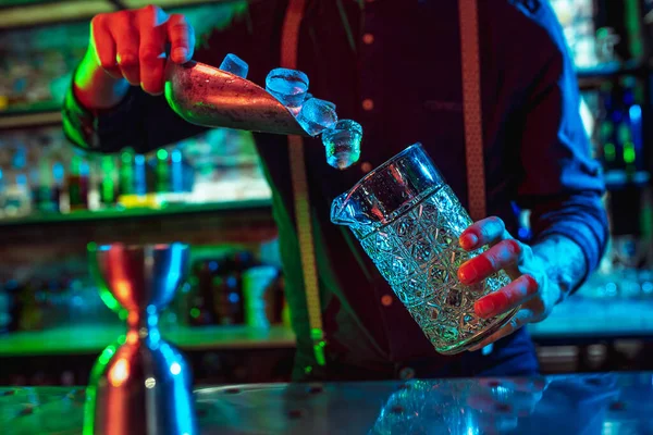 Primer plano de barman termina preparación de cóctel alcohólico en luz de neón multicolor — Foto de Stock