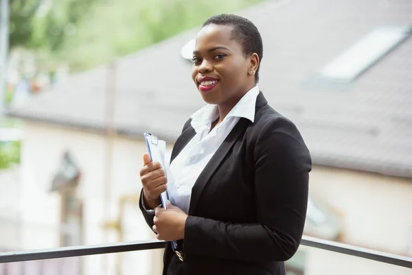 Empresária afro-americana em traje de escritório sorrindo, parece confiante e feliz, bem sucedida — Fotografia de Stock