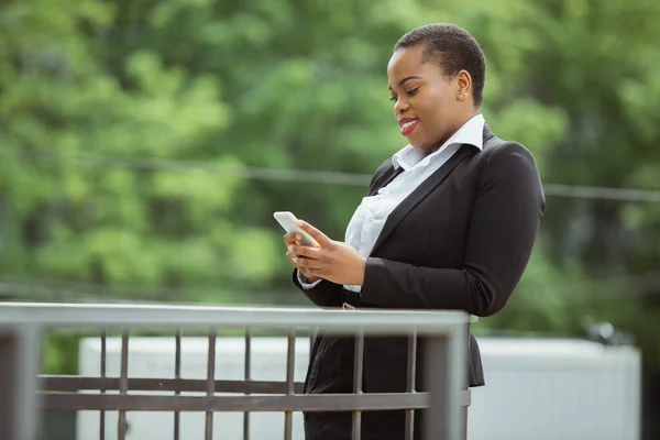 Mujer de negocios afroamericana en traje de oficina sonriendo, se ve confiada y feliz, exitosa —  Fotos de Stock