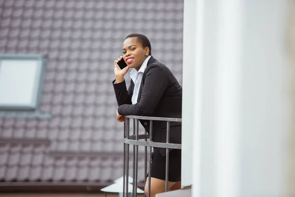 Mujer de negocios afroamericana en traje de oficina sonriendo, se ve confiada y feliz, exitosa —  Fotos de Stock