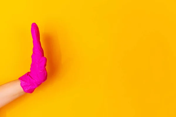 Mão na luva de borracha rosa saudação, acenando isolado no fundo do estúdio amarelo com copyspace . — Fotografia de Stock