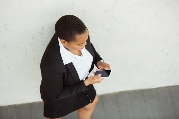 Mujer de negocios afroamericana en traje de oficina sonriendo, se ve confiada y feliz, exitosa —  Fotos de Stock