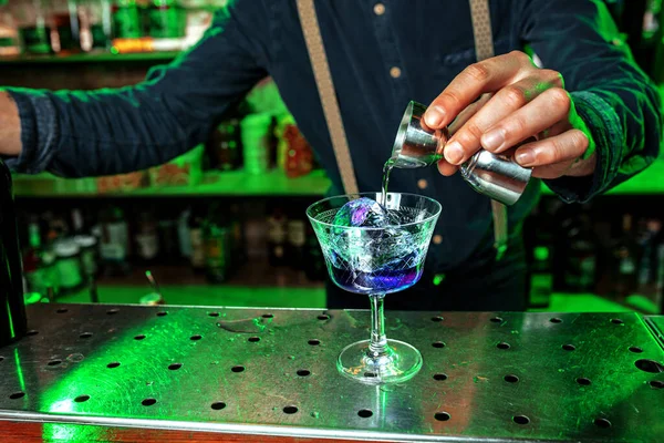 Primer plano de barman termina la preparación de cóctel alcohólico, verter bebida con disparo en luz de neón multicolor, se centran en el vidrio — Foto de Stock