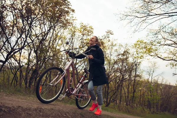 Młoda kobieta bawiąca się w pobliżu parku krajobrazowego, jazda na rowerze, podróże w wiosenny dzień — Zdjęcie stockowe