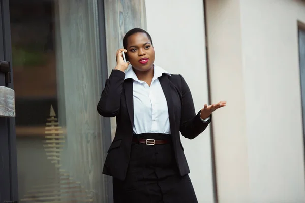 Mujer de negocios afroamericana en traje de oficina sonriendo, se ve confiada y feliz, exitosa —  Fotos de Stock