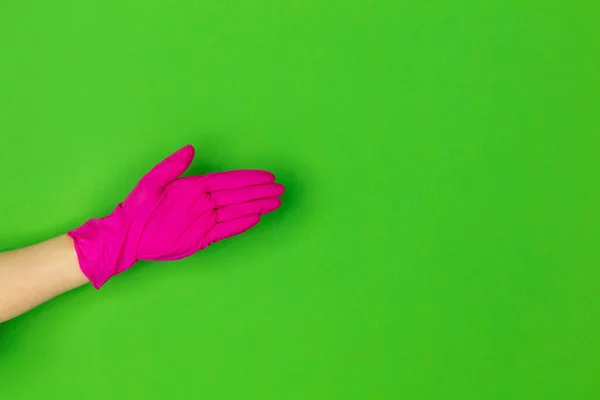 Рука в рожевій гумовій рукавичці вітання ізольовані на зеленому студійному фоні з копіспадом . — стокове фото