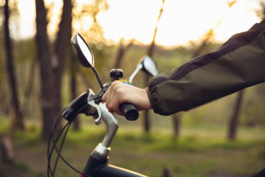 Kırsal park yakınlarında eğlenen, bisiklete binen, bahar günü seyahat eden genç adama yakın durun.