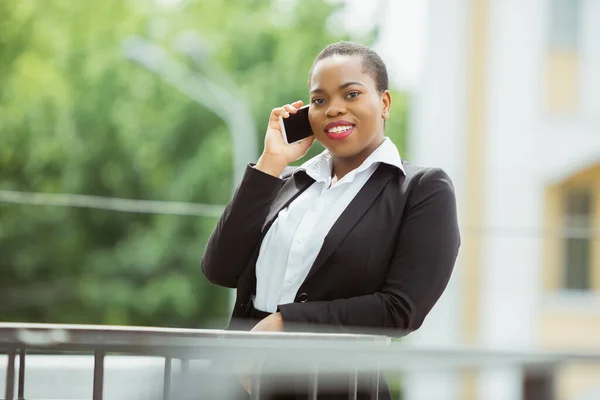 Mujer de negocios afroamericana en traje de oficina sonriendo, se ve confiada y feliz, exitosa —  Fotos de Stock